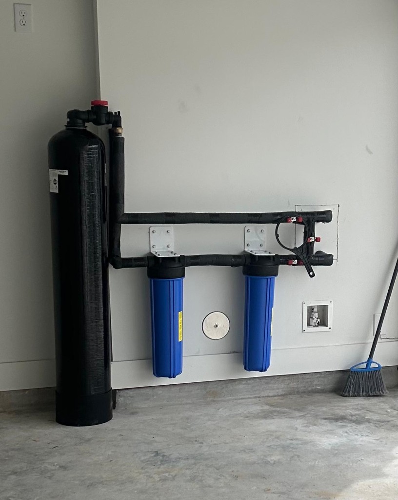 Whole-home filter tank with dual big-blue pre-filters installed in a garage
