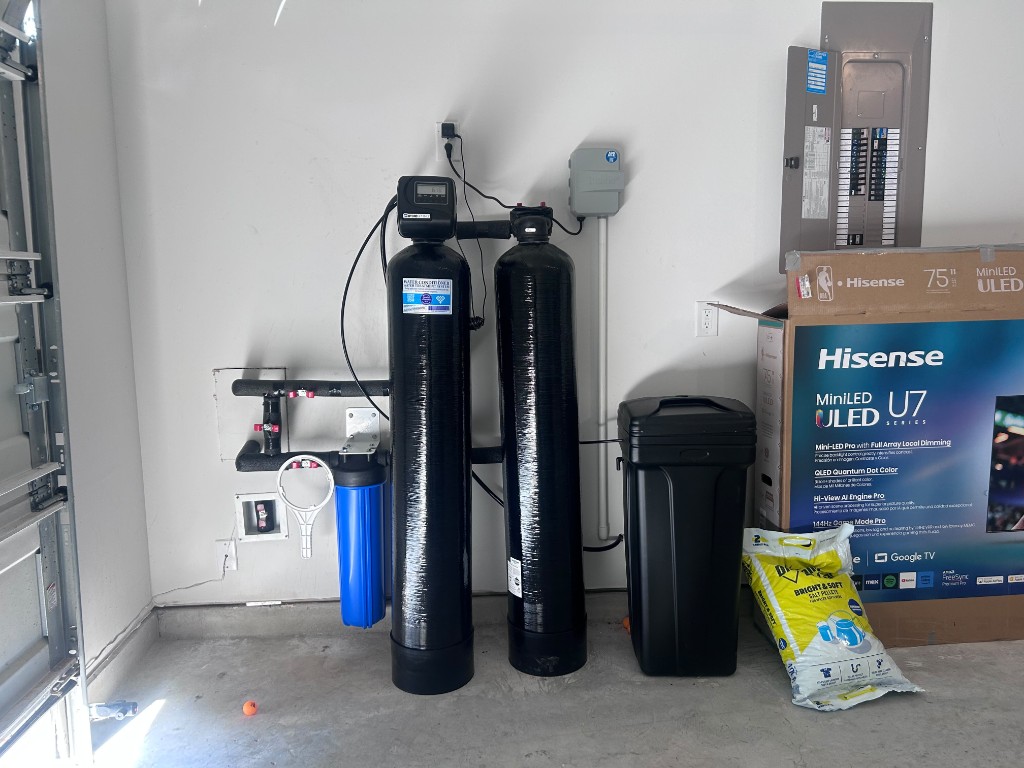 Twin-tank water softener with pre-filter and brine tank installed in a Houston garage